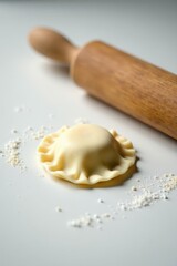 Homemade Ravioli Preparation A Close-Up View of a Single, Uncooked Ravioli Beside a Wooden Rolling Pin and Flour Dust