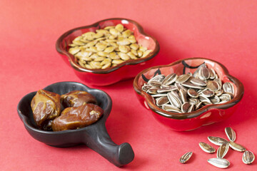 Chinese New Year Snack Bowls with Seeds and Dates on Red Background