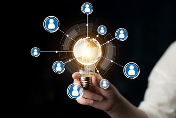 A person holds a glowing light bulb symbolizing innovation amidst social connection icons. This image represents the convergence of ideas, collaboration, and modern communication. Crux