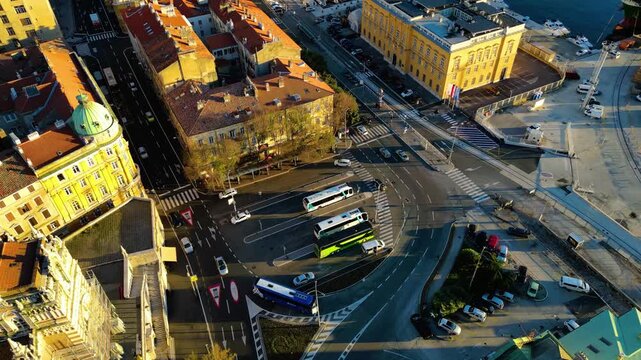 Aerial view of Rijeka, Croatia, showcasing its bustling port, historic architecture, and urban sprawl against the Adriatic Sea and mountains during a golden autumn afternoon.