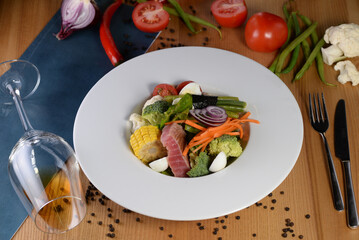 warm tuna salad on a plate against the background of wine in a glass and food decor