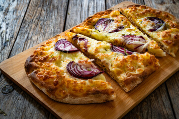 Pinsa bianca white pizza with red onion and oregano on wooden table	