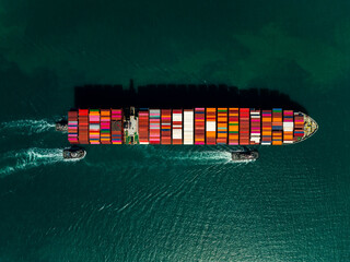 Aerial top down view of cargo container ship sailing with tugboats in emerald sea © SHUTTER DIN