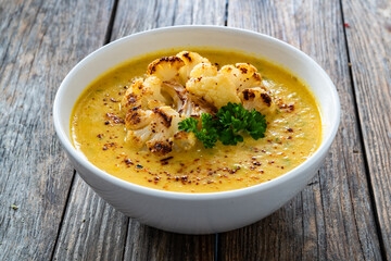 Cauliflower cream soup on wooden table