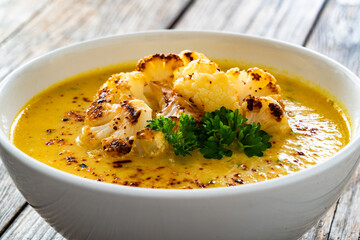 Cauliflower cream soup on wooden table