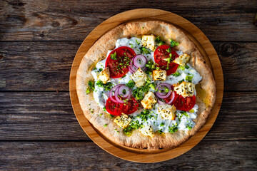 Pizza with feta cheese, tomatoes, red onion and broccoli dip on wooden table. Top view	