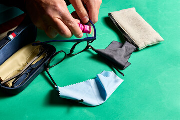 Cleaning glasses. A man's hands with a small microfiber cloth cleaning the lenses of a pair of glasses.