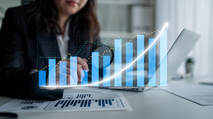 A businesswoman evaluates financial data using a laptop and visual graphs in a modern office setting, illustrating growth and success in her analysis. Impute