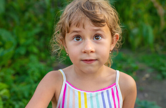 A child portrait squints on the street. Selective focus.