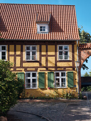 Traditional Yellow House With Red Tile Roof And Green Shutters In Stralsund