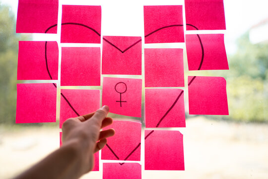 Woman composing heart shape with pink sticky notes celebrating womanhood - Powered by Adobe