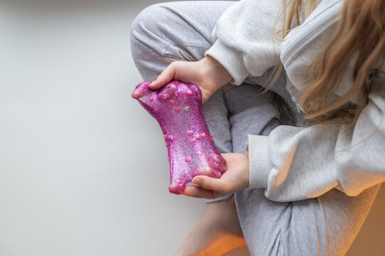 A close up of a small child playing with slime, stretching, squeezing, and exploring its texture.