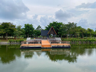 Fototapeta premium Dark wooden pavilion with a stepped roof on a floating wooden platform over calm water in PIK 2 recreation park.