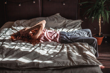 Sad young woman lying in bed