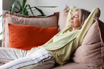 Beautiful middle age Woman relaxed and sitting on Sofa in living room at home