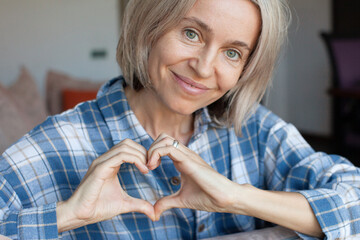 Smiling woman making heart shape with her hands