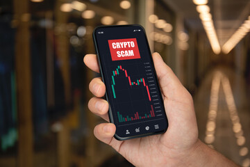 Male hand hold phone with chart scam crypto coins screen