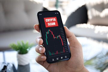 man hand hold phone with chart scam crypto coins on screen