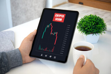 male hand hold computer tablet with chart scam crypto coins