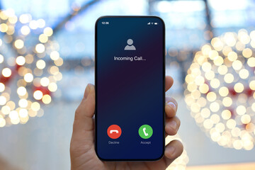 man hand hold phone with incoming call on screen Christmas