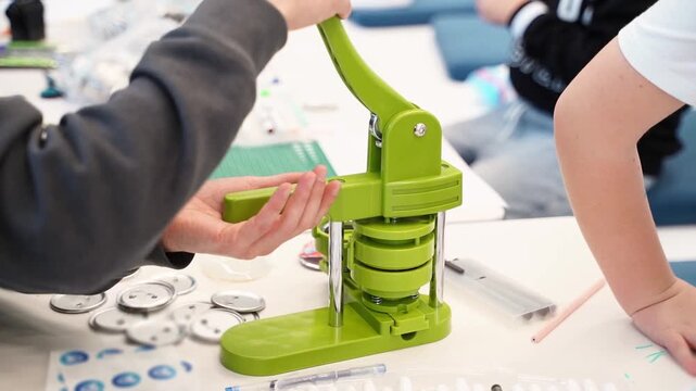 Hands using green button maker, demonstrating crafting process with engaging camera movement