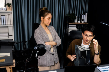 Serious face of working sales manager with secretary taking overworked folder paper at over late night checking collected signing document for board company keeping database file at office. Infobahn.