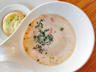 Norwegian fish soup creamy salmon chowder in white bowl on wooden table horizontal