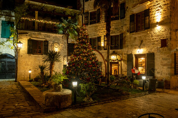 Outdoor Christmas tree decorated with lights in a historic plaza in Kotor