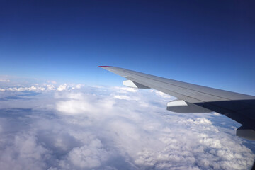 View from the window of a high-flying from left to right aircraft of an endless blue sky with clouds below