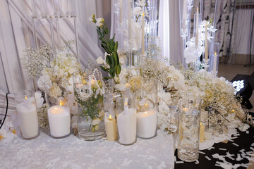 Elegant white floral arrangement with candles at a celebration event in a stylish venue