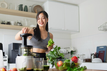 Young woman extracting vegetable juice in the kitchen