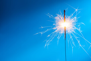 Obraz premium A brightly burning sparkler on a blue background