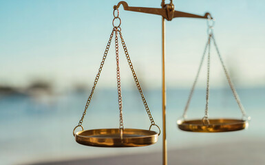 Elegant antique brass scales of justice balanced against a serene, soft blue horizon representing fairness and equilibrium