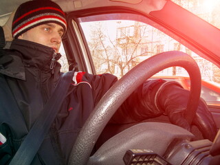 young man in winter clothes driving an old car