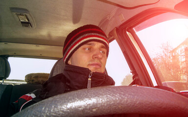young man in winter clothes driving an old car