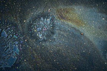 Patterns on the Ground After Rain Show Colors From Oil in a City Street During a Cloudy Day