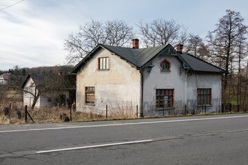 Old family house with cracked plaster in landscape with road