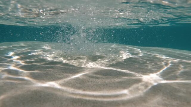 A shimmering macro shot of bright sunlight refracting and creating dancing caustic patterns on a smooth surface under rippling water liquidmotion, clean, illumination