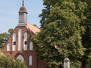 kleine typisch norddeutsche Kirche neben einer gro&szlig;en Linde