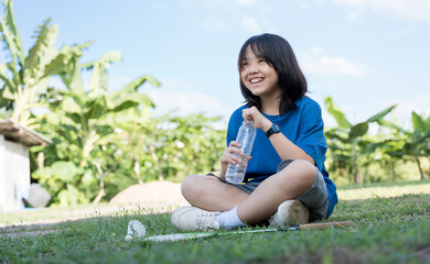 A cheerful girl hydrating with a water bottle while taking a break from badminton outdoors.