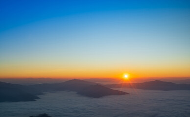 Golden sunrise above fog-filled mountains with soft warm tones and peaceful atmosphere.