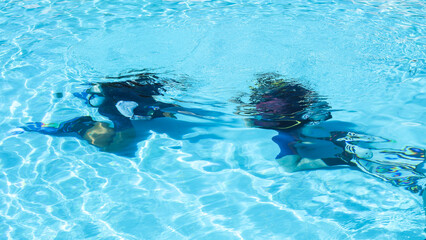 diving instructor teaches a person underwater in a swimming pool.