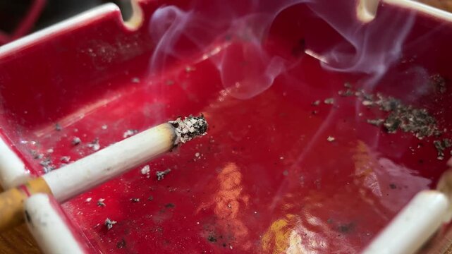 a lit cigarette on a red ashtray