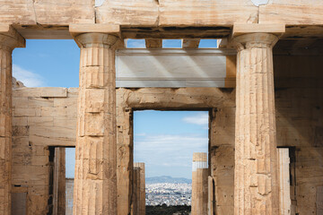 A detailed close-up of the Doric columns and marble architecture of the Parthenon at the Acropolis in Athens, with view through portal of cityscape sprawl of Athens, Greece.