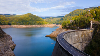 Aerial photography of Vidraru dam, in Romania. Photography was shot from a drone from above canyon at Vidraru lake with the dam and the lake in the view and mountains in the background.