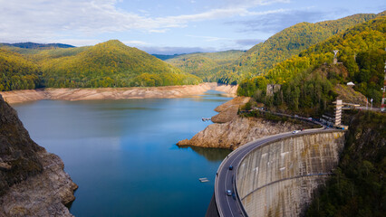 Aerial photography of Vidraru dam, in Romania. Photography was shot from a drone from above canyon at Vidraru lake with the dam and the lake in the view and mountains in the background.