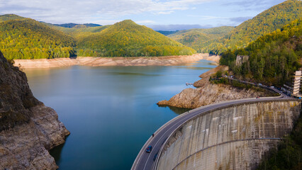 Aerial photography of Vidraru dam, in Romania. Photography was shot from a drone from above canyon at Vidraru lake with the dam and the lake in the view and mountains in the background.