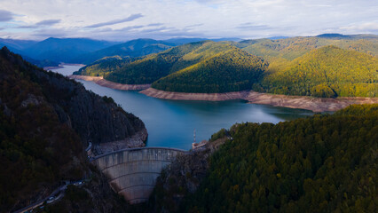 Aerial photography of Vidraru dam, in Romania. Photography was shot from a drone from above canyon at Vidraru lake with the dam and the lake in the view and mountains in the background.