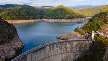 Aerial photography of Vidraru dam, in Romania. Photography was shot from a drone from above canyon at Vidraru lake with the dam and the lake in the view and mountains in the background.
