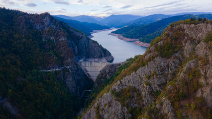 Aerial photography of Vidraru dam, in Romania. Photography was shot from a drone from above canyon at Vidraru lake with the dam and the lake in the view and mountains in the background.